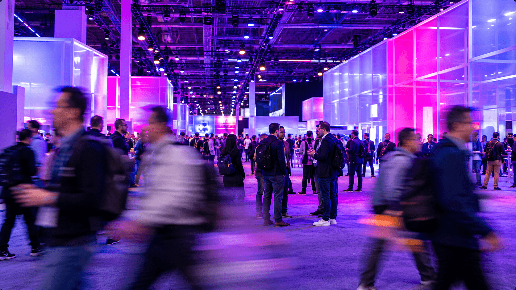 The AWS re:Invent expo floor — attendees moving between brightly lit exhibitor booths.