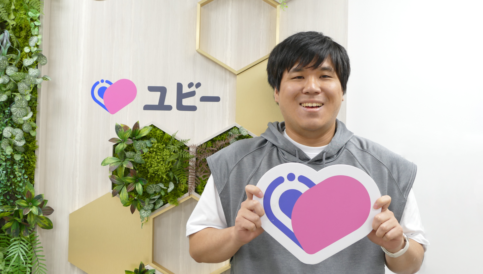 ユビーのロゴボードを手にするUbie株式会社 データエンジニアの由川さん